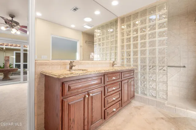 a bathroom with a granite countertop sink a mirror and shower