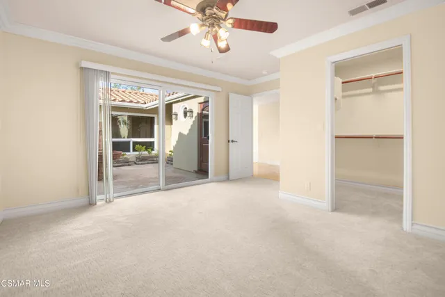 an empty room with chandelier fan and windows