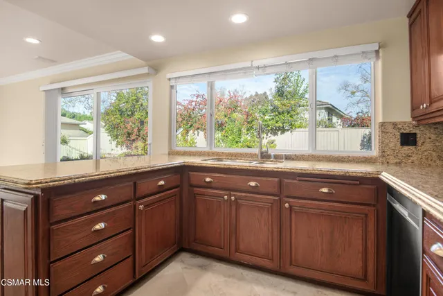 a kitchen with granite countertop wooden cabinets a sink and a large window