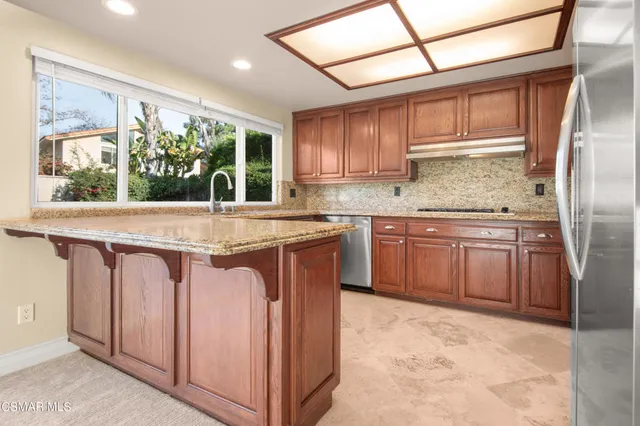 a kitchen with stainless steel appliances granite countertop a stove a sink and a refrigerator