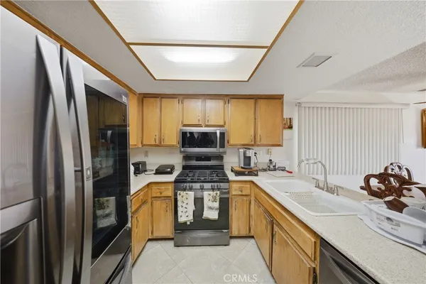 a kitchen with a sink stainless steel appliances cabinets and a window