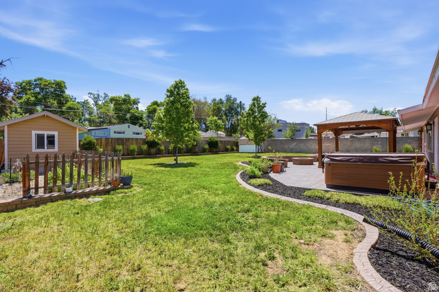 6889 South Village Road Salt Lake City, UT 84121 - Photo 33 of 44 Expansive lawn with a paver patio featuring a hot tub and a wooden gazebo