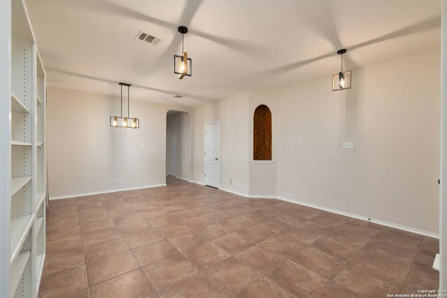 an empty room with windows and ceiling fan
