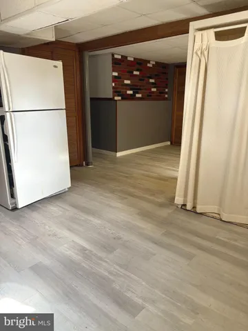a view of a refrigerator in kitchen and an empty room