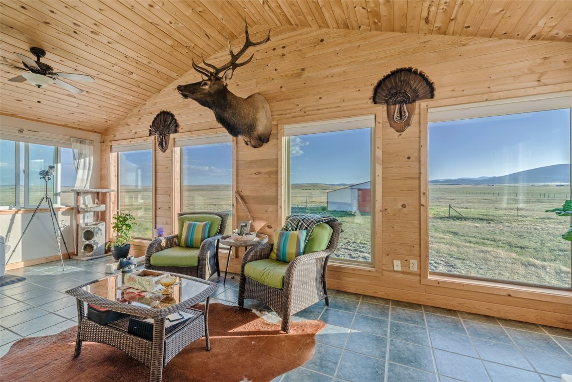 465 Litmer Road Jefferson, CO 80456 - Photo 15 of 50 Sunroom / solarium with vaulted ceiling, wooden walls, wooden ceiling, a mountain view, and stone finish floors