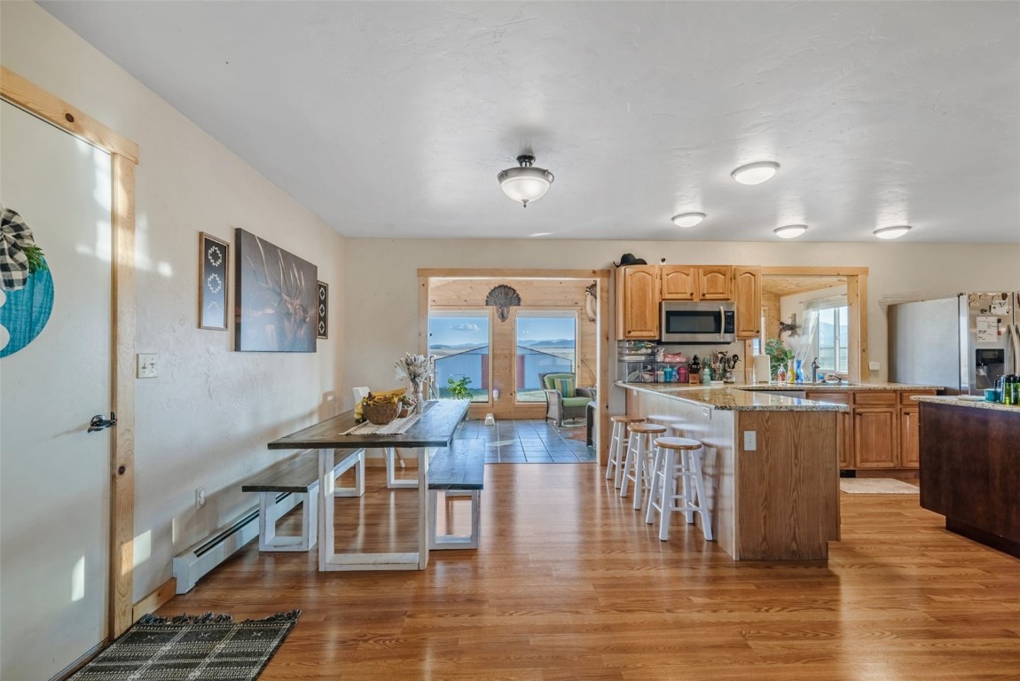 465 Litmer Road Jefferson, CO 80456 - Photo 16 of 50 Kitchen with appliances with stainless steel finishes, baseboard heating, a breakfast bar area, and light wood-style flooring