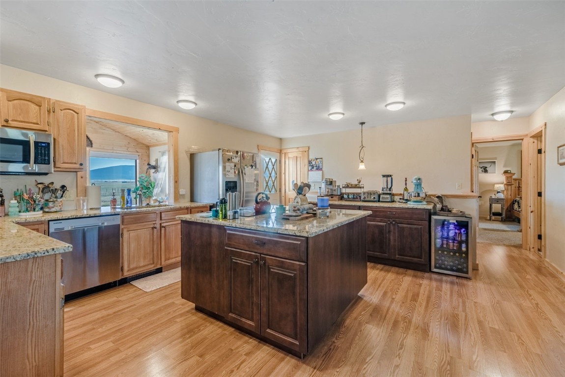 465 Litmer Road Jefferson, CO 80456 - Photo 17 of 50 Kitchen with stainless steel appliances, wine cooler, light wood-style flooring, and light stone countertops