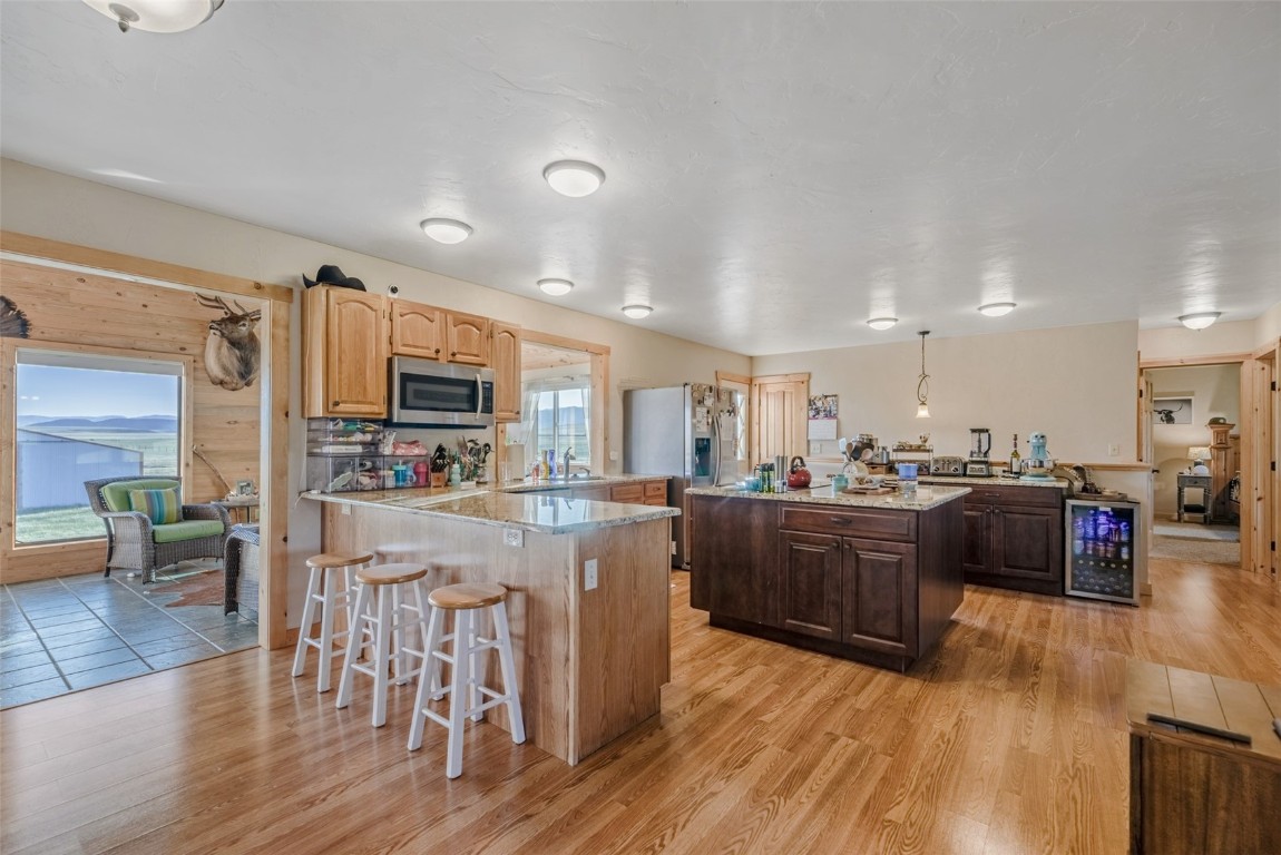 465 Litmer Road Jefferson, CO 80456 - Photo 2 of 50 Kitchen with appliances with stainless steel finishes, wine cooler, a peninsula, a kitchen island, and a breakfast bar