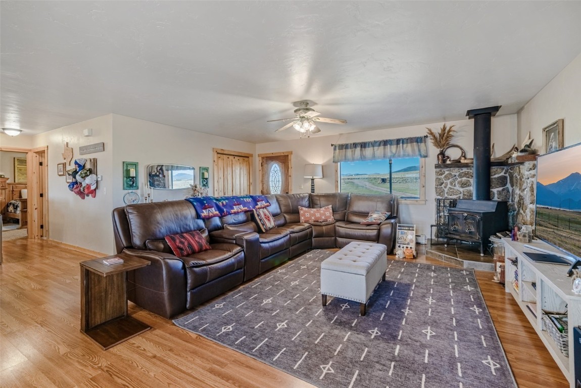 465 Litmer Road Jefferson, CO 80456 - Photo 4 of 50 Living room with wood finished floors, a wood stove, and a ceiling fan