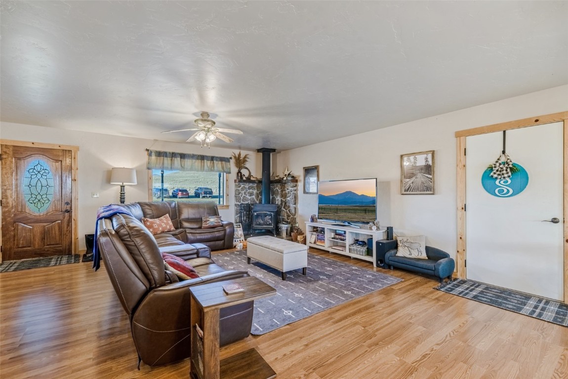 465 Litmer Road Jefferson, CO 80456 - Photo 9 of 50 Living area featuring wood finished floors, a wood stove, and a ceiling fan