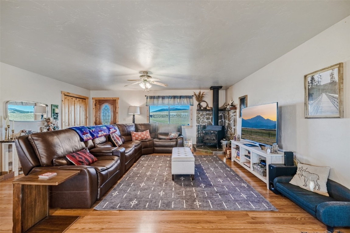 465 Litmer Road Jefferson, CO 80456 - Photo 10 of 50 Living area with a wood stove, wood finished floors, and ceiling fan