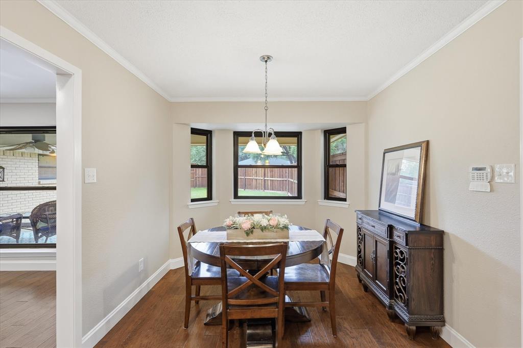 7200 Tamarack Road Benbrook, TX 76116 - Photo 15 of 38 Eat-in kitchen dining area featuring a bay window, wood-finish flooring, and a contemporary chandelier.