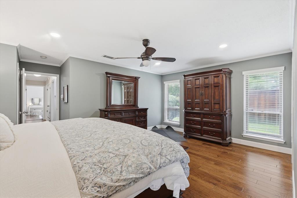 7200 Tamarack Road Benbrook, TX 76116 - Photo 19 of 38 Primary bedroom featuring wood finished flooring, two windows that offer plenty of natural lighting, and crown molding.