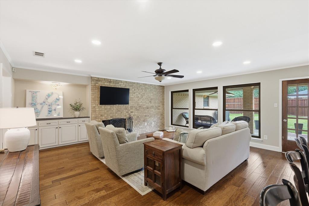 7200 Tamarack Road Benbrook, TX 76116 - Photo 10 of 38 Living room featuring built-in cabinetry, a brick wood-burning fireplace and a wall of windows providing ample natural light.