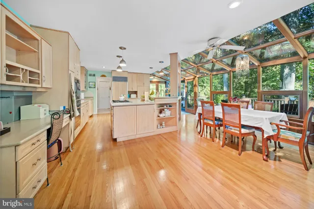 a large white kitchen with wooden floor and stainless steel appliances