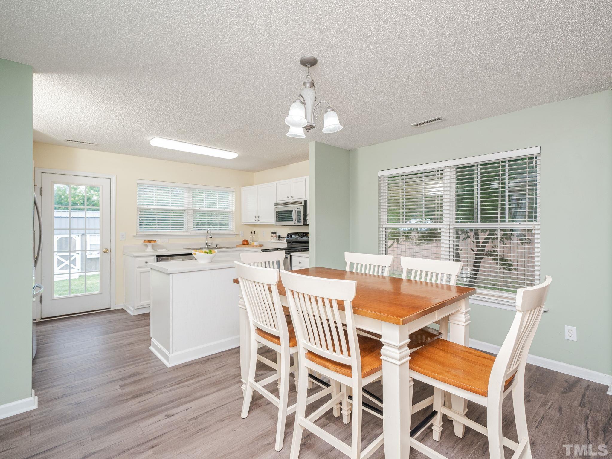 4117 Hopper Street Raleigh, NC 27616 - Photo 5 of 30 a dining room with wooden floor and a kitchen