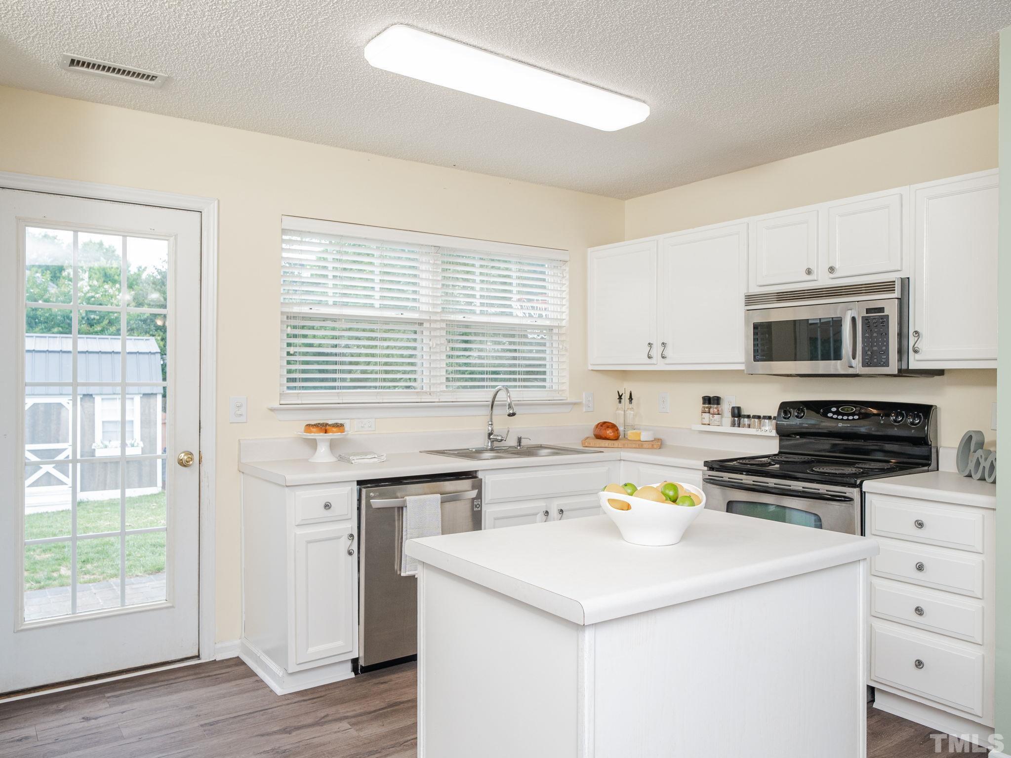 4117 Hopper Street Raleigh, NC 27616 - Photo 6 of 30 a kitchen with a stove a sink and a microwave