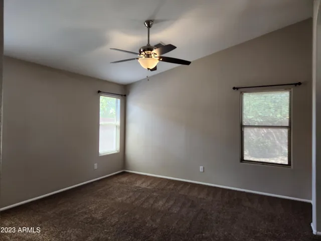 an empty room with windows and chandelier fan