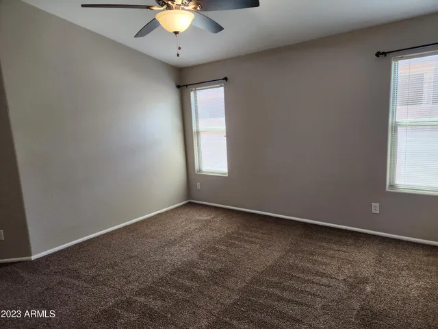 an empty room with windows and chandelier fan