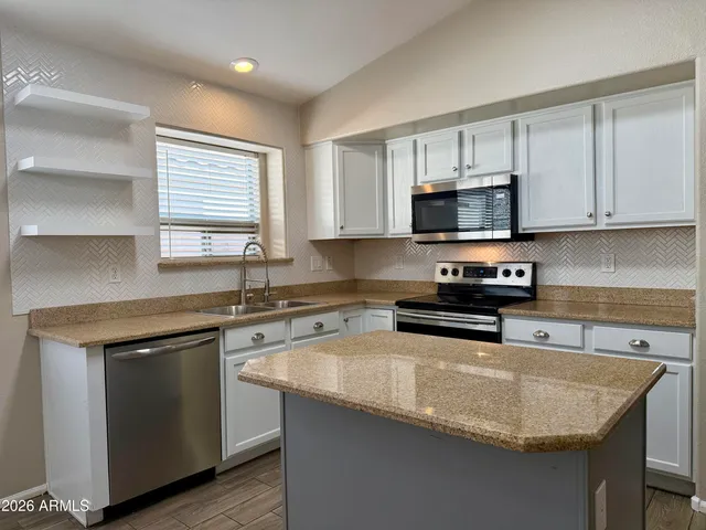 a kitchen with stainless steel appliances granite countertop a sink stove and microwave