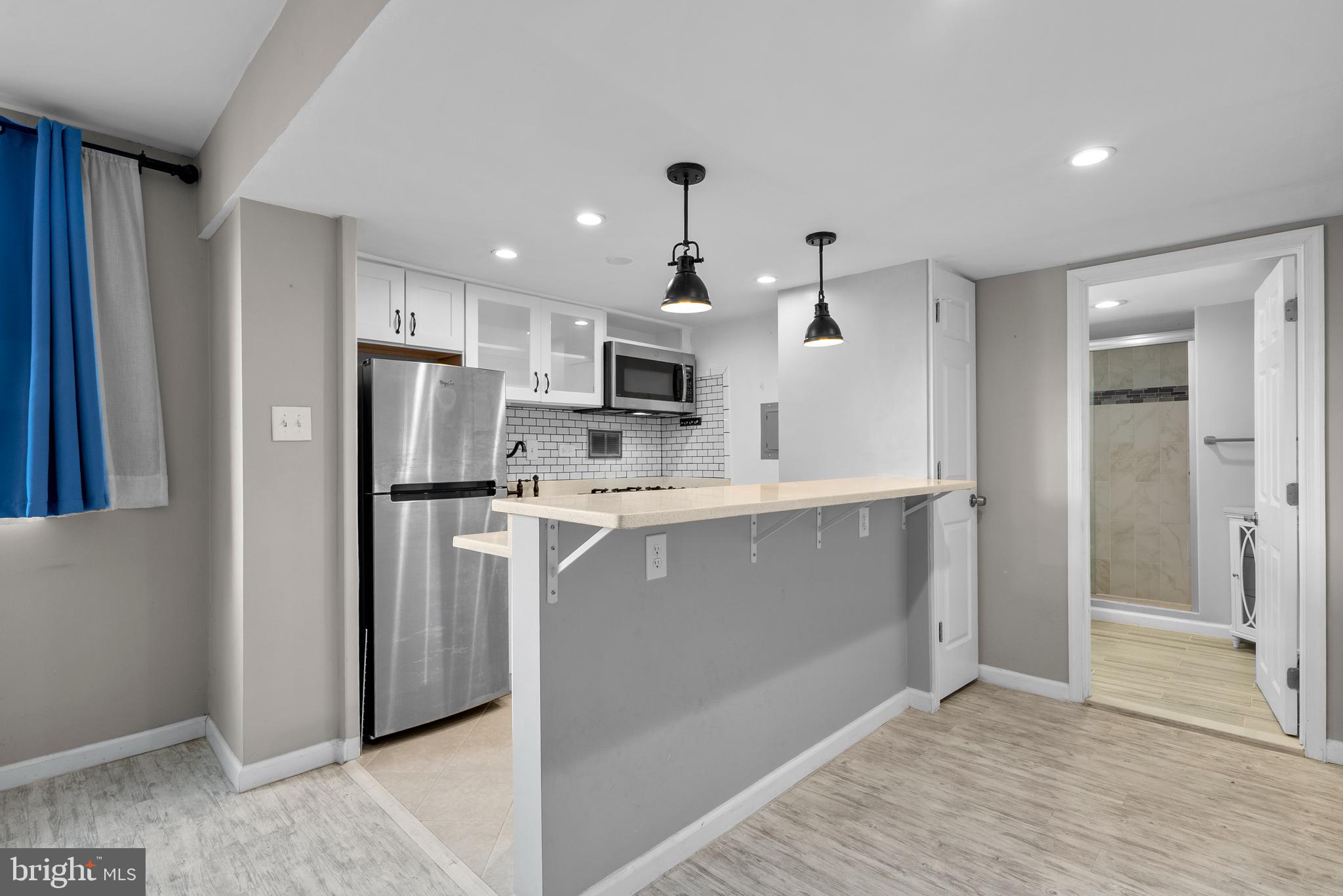 1420 N Street Northwest, Unit 914 Washington, DC 20005 - Photo 5 of 23 a kitchen with kitchen island white cabinets and refrigerator