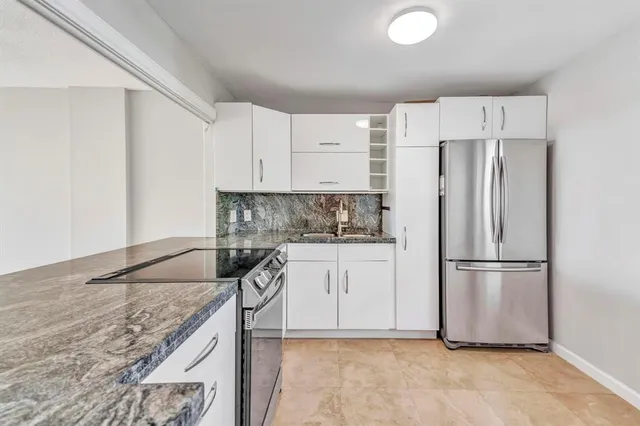 a kitchen with granite countertop a refrigerator sink and cabinets