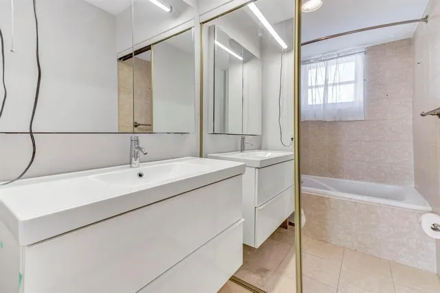 a bathroom with a double vanity sink a mirror and a bathtub