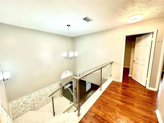 a view of a hallway with wooden floor and staircase