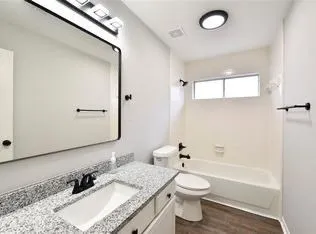 a bathroom with a granite countertop sink a toilet and shower