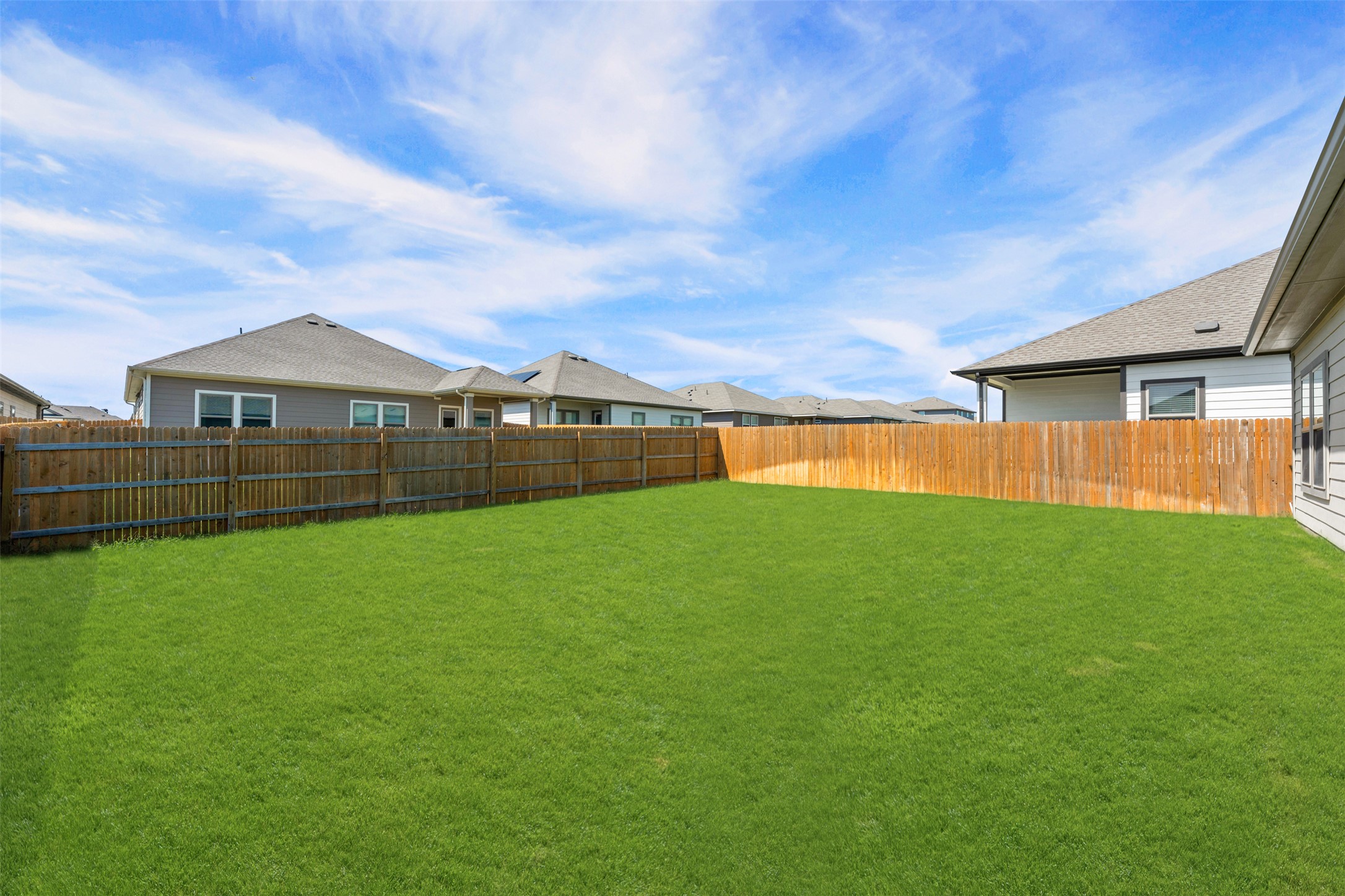 236 Lazy Lizzy Road Jarrell, TX 76537 - Photo 25 of 27 A spacious backyard with vibrant green grass and a sturdy wood fence, offering ample room for outdoor activities.