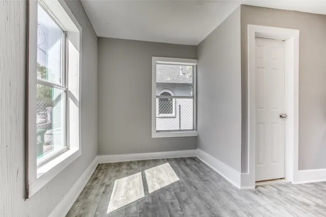 a view of an empty room and window a ceiling fan and wooden floor
