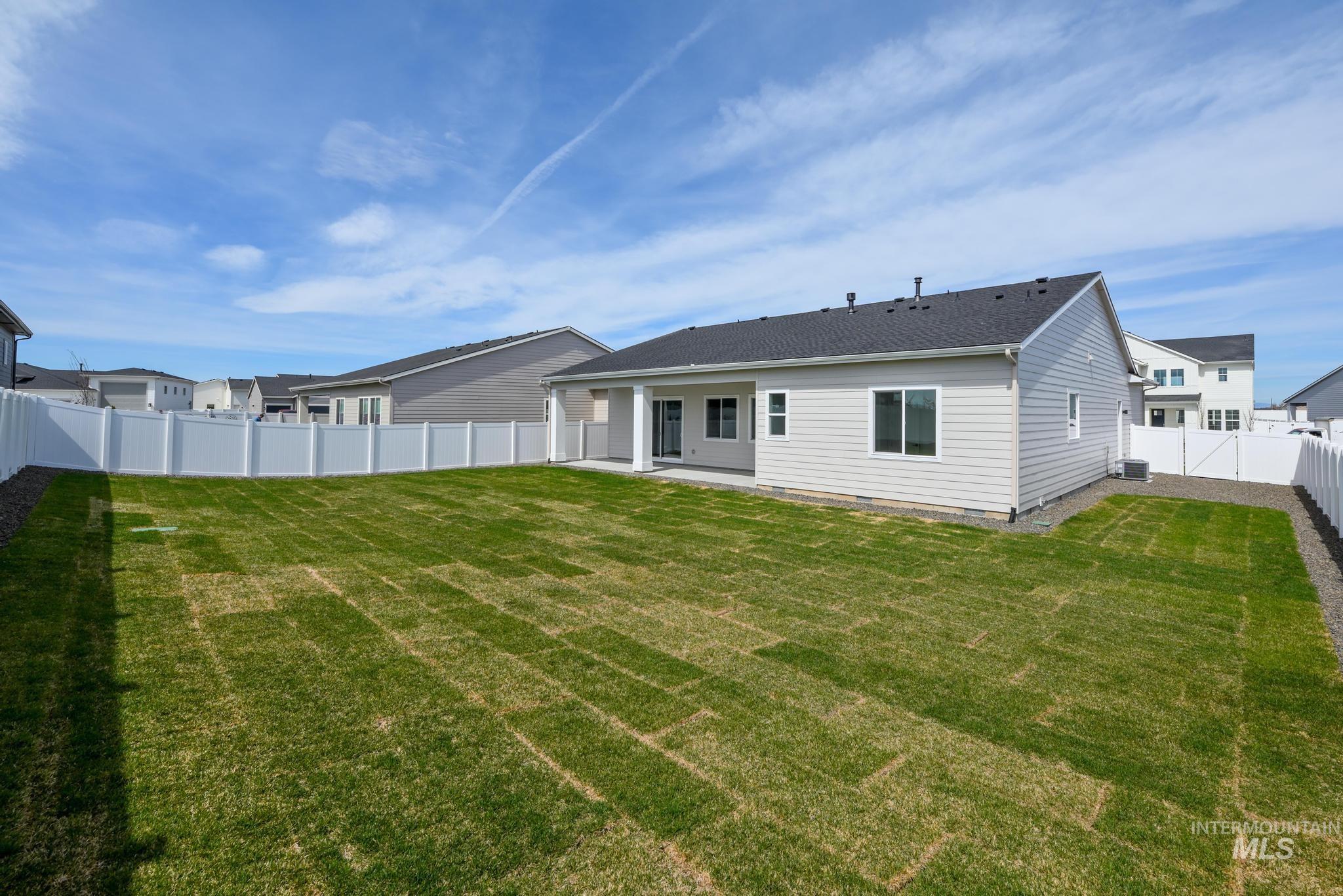 1195 West Switchgrass Drive Meridian, ID 83642 - Photo 12 of 22 Expansive backyard featuring newly laid sod, a full white privacy fence, and a concrete patio