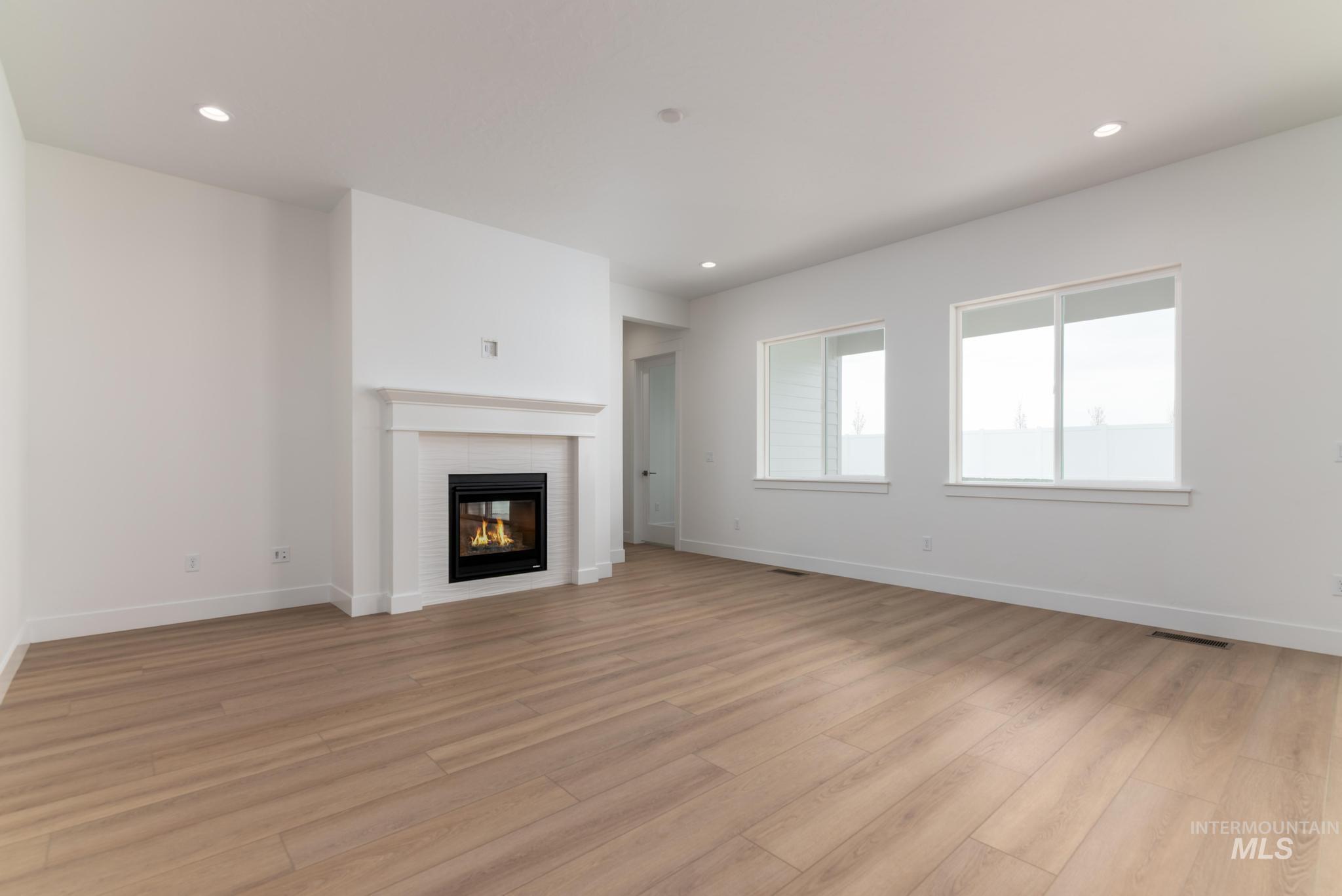 1195 West Switchgrass Drive Meridian, ID 83642 - Photo 2 of 22 Living space featuring a white mantel fireplace with white subway tile surround, recessed lighting, and wood-finish flooring