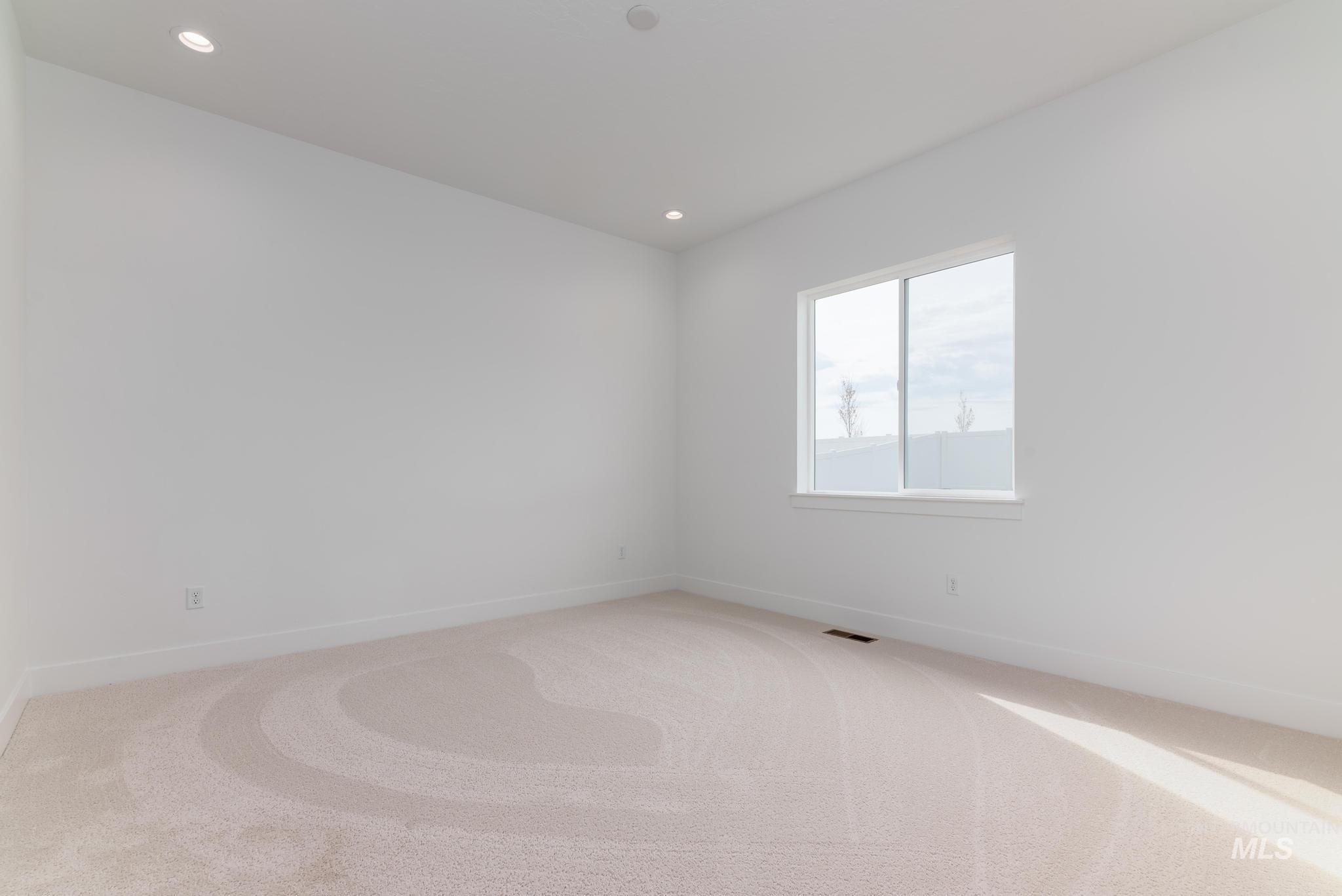 1195 West Switchgrass Drive Meridian, ID 83642 - Photo 6 of 22 Bright room featuring a large window, recessed lighting, white walls, white baseboards, and light-colored carpeting