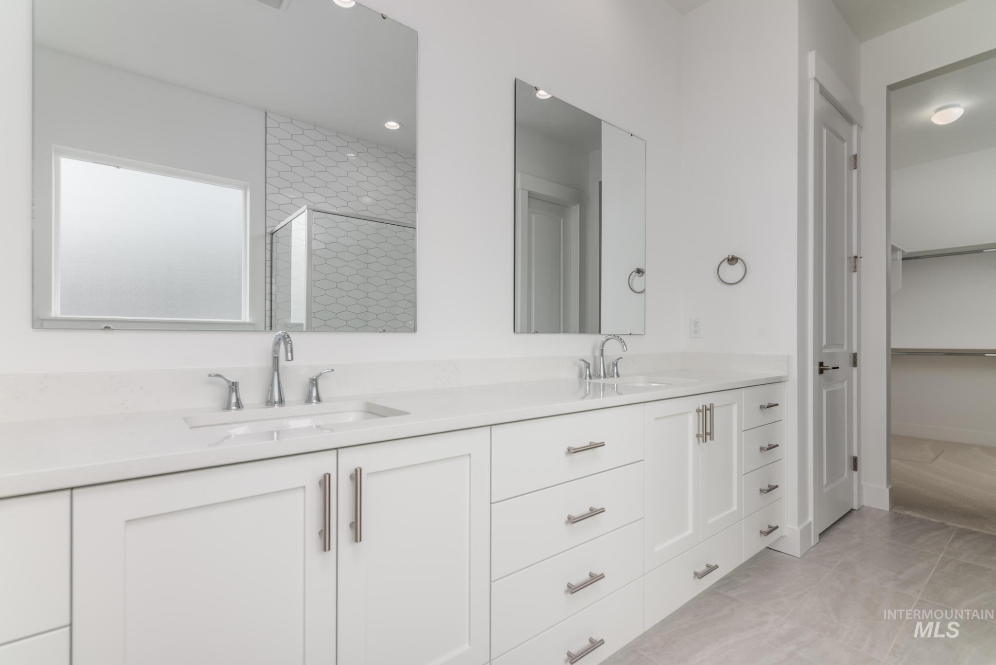 1195 West Switchgrass Drive Meridian, ID 83642 - Photo 8 of 22 Double vanity featuring white cabinetry with brushed nickel hardware, integrated sinks, and polished chrome faucets