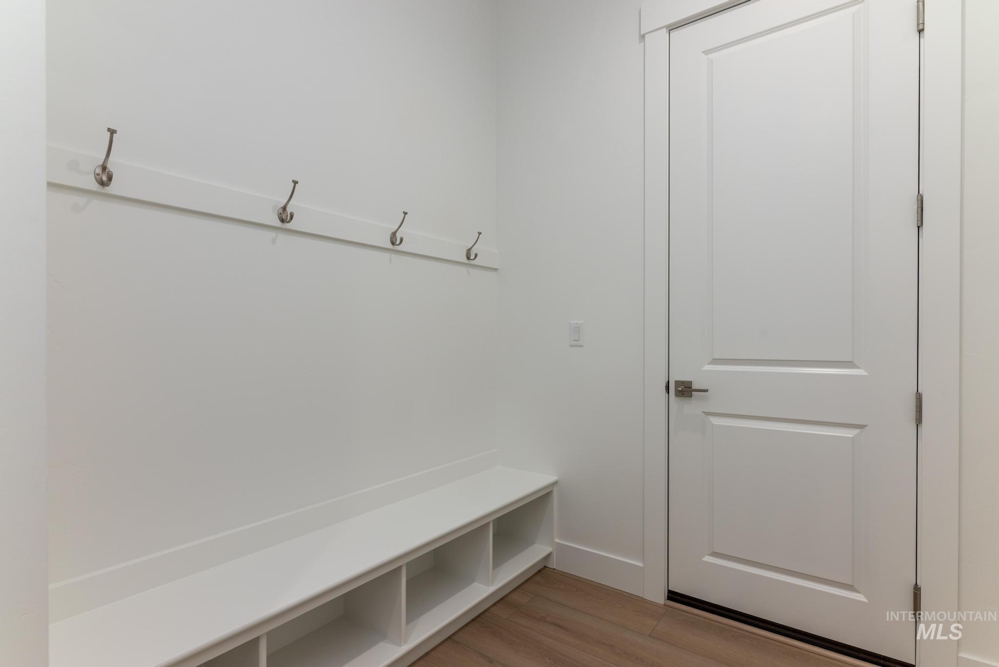 1195 West Switchgrass Drive Meridian, ID 83642 - Photo 10 of 22 Entryway featuring a built-in bench with open storage compartments, wall-mounted coat hooks, and a solid white door with a silver handle
