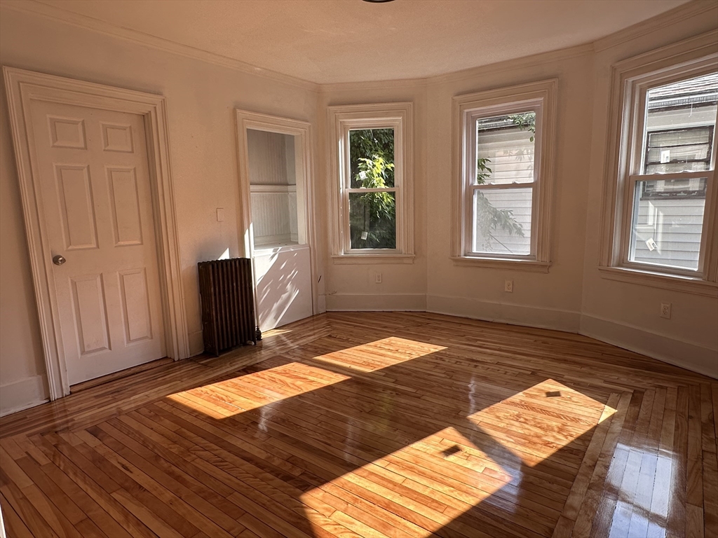 46 Theodore Street Boston, MA 02124 - Photo 6 of 32 a view of an empty room with wooden floor and a window