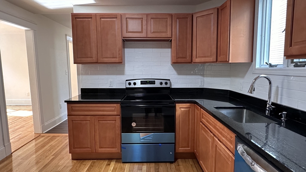 46 Theodore Street Boston, MA 02124 - Photo 10 of 32 a kitchen with granite countertop wooden cabinets and a stove top oven