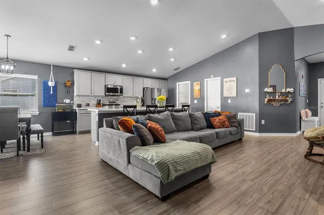 a living room with stainless steel appliances furniture and a wooden floor