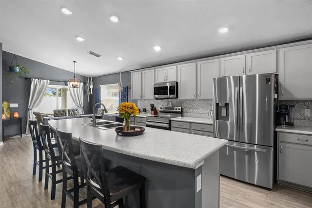 a kitchen with refrigerator a sink and chairs