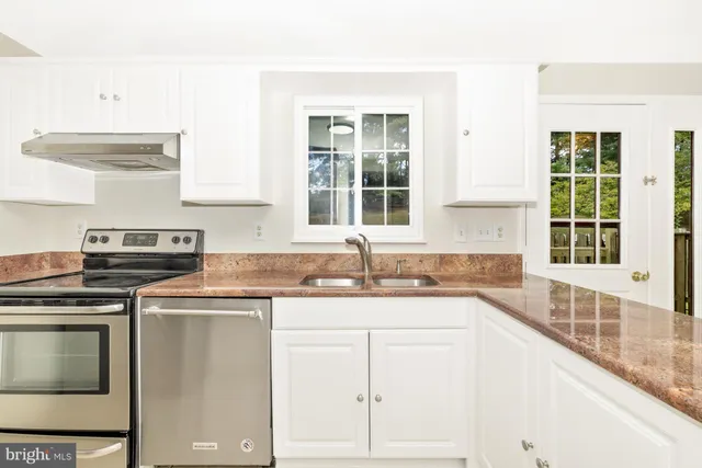 a kitchen with granite countertop a sink stainless steel appliances and cabinets
