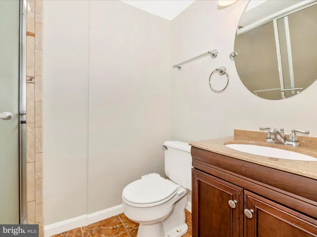 a bathroom with a granite countertop toilet sink mirror and vanity