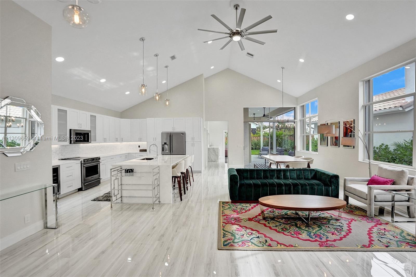 a living room with stainless steel appliances kitchen island granite countertop a stove a couch and a dining table with wooden floor