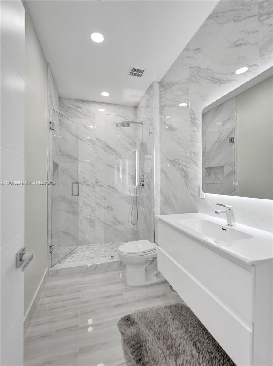 6688 Northwest 25th Court Boca Raton, FL 33496 - Photo 31 of 64 a bathroom with a bathtub shower sink vanity and a toilet