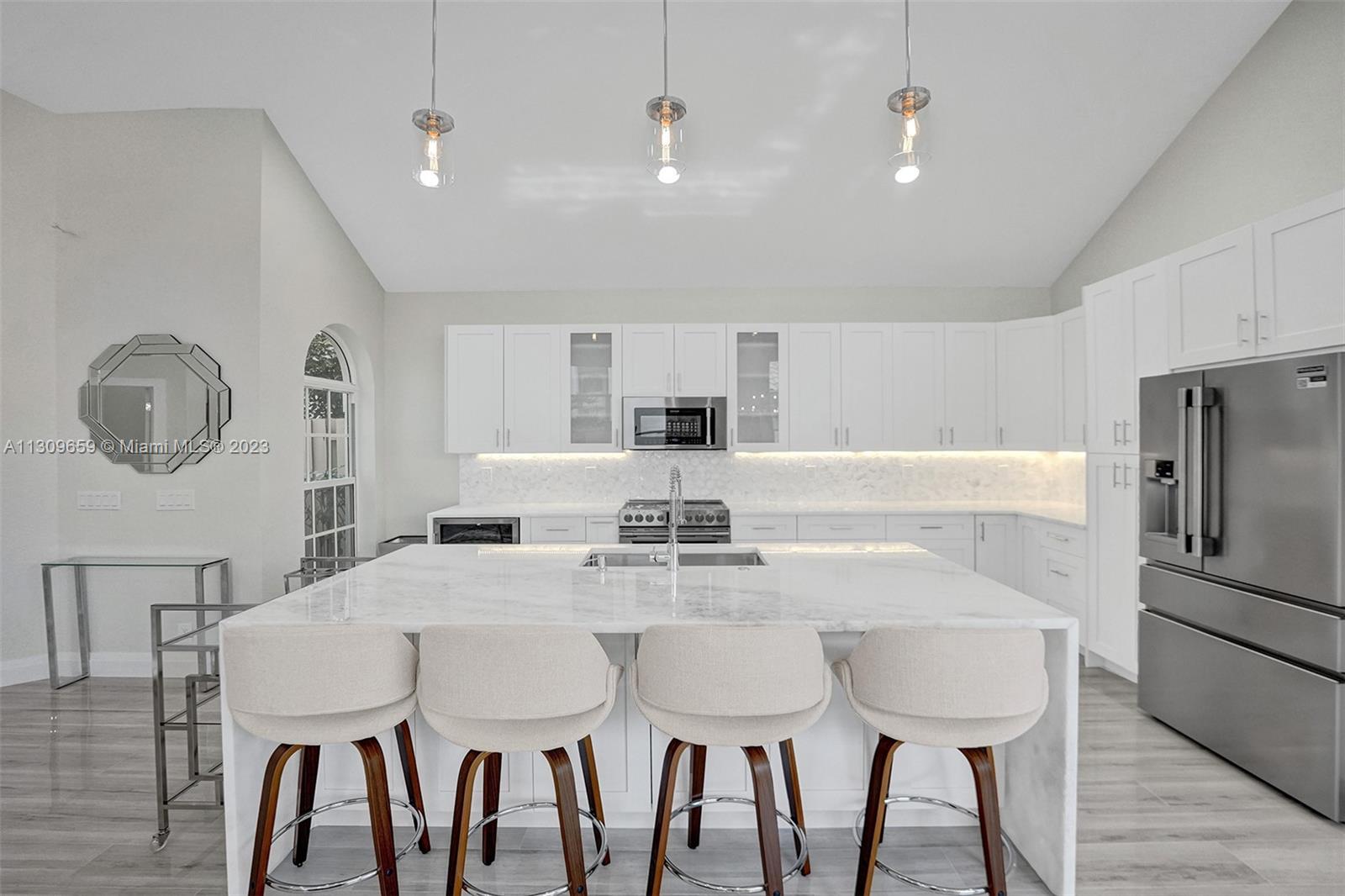 6688 Northwest 25th Court Boca Raton, FL 33496 - Photo 4 of 64 a kitchen with stainless steel appliances a table chairs and a refrigerator
