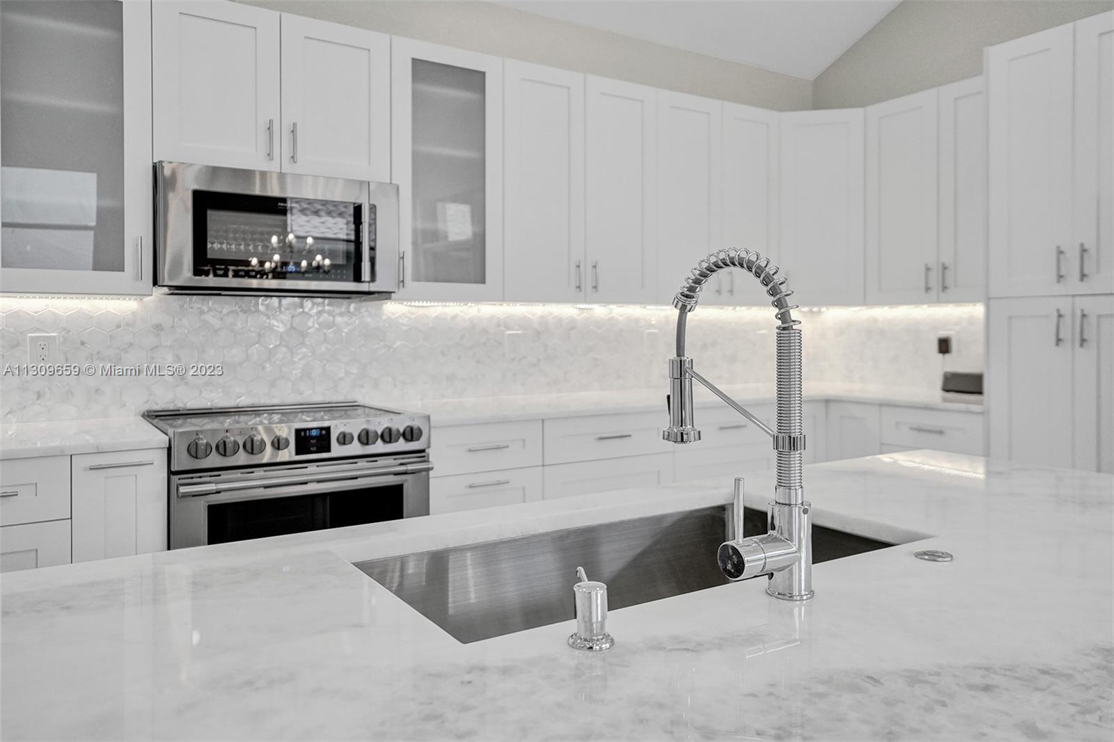 6688 Northwest 25th Court Boca Raton, FL 33496 - Photo 6 of 64 a kitchen with granite countertop a stove and a sink