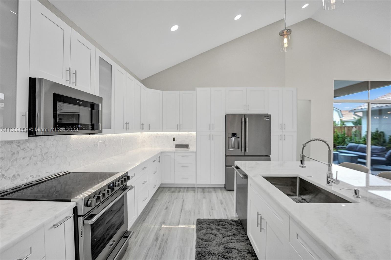 6688 Northwest 25th Court Boca Raton, FL 33496 - Photo 7 of 64 a kitchen with granite countertop a sink and a stove top oven