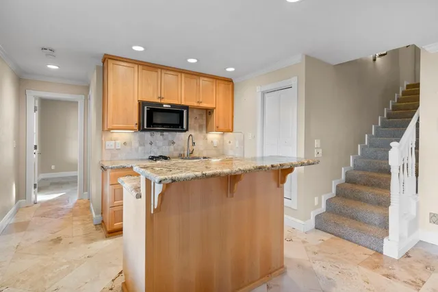 a view of a kitchen with stainless steel appliances granite countertop a stove a sink and a microwave