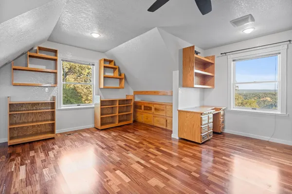 an empty room with chandelier fan and windows