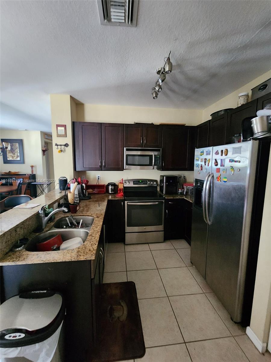 13986 Southwest 276th Street Homestead, FL 33032 - Photo 10 of 28 a kitchen with a sink a stove and refrigerator